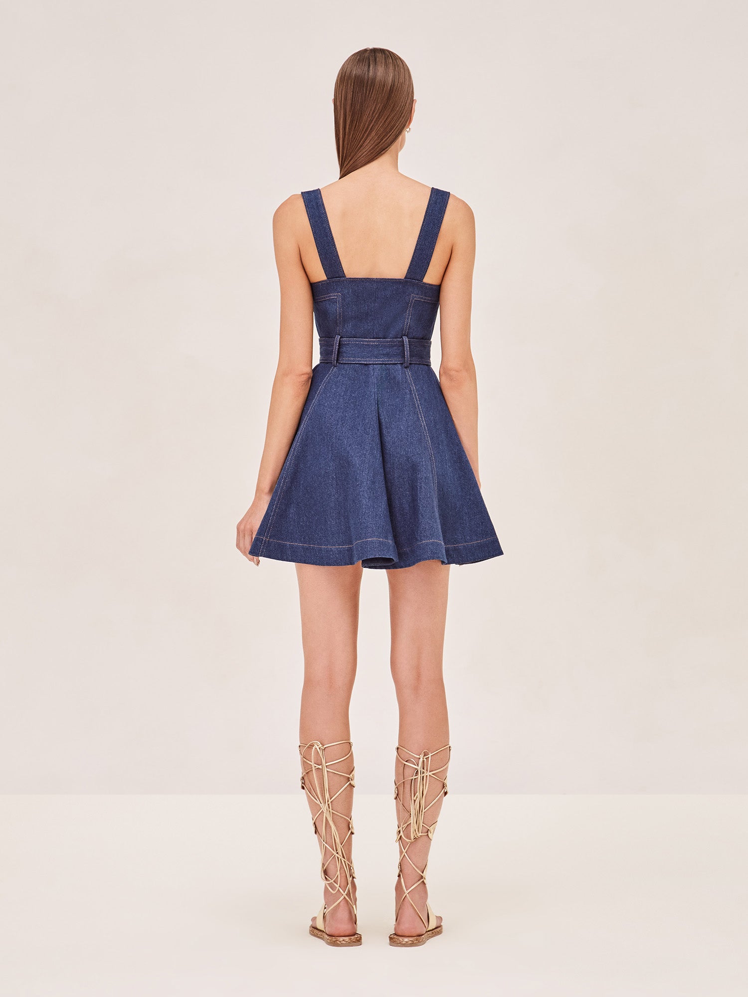ALEXIS Danni sleeveless mini dress in denim with waist sash belt and gold button accents. back image